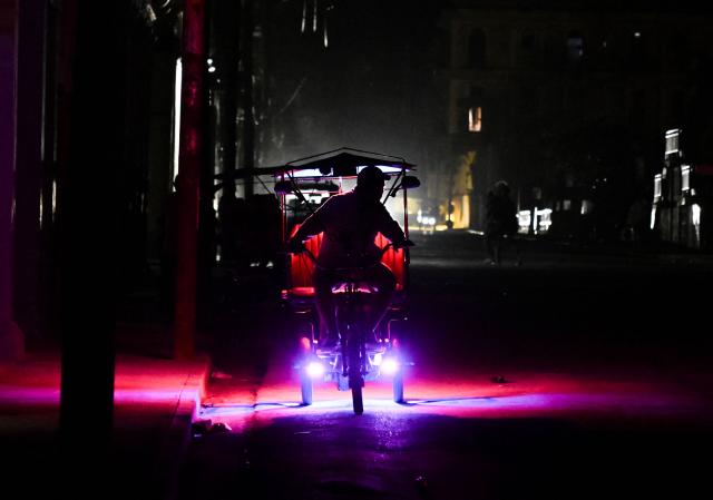 A man rides his bike during a nation wide blackout in Havana on March 21, 2026. A power outage struck the entire island of Cuba on March 21, 2026, the energy ministry said, in the second nationwide blackout in less than a week as its grid struggles under a US oil blockade. (Photo by Yamil LAGE / AFP)