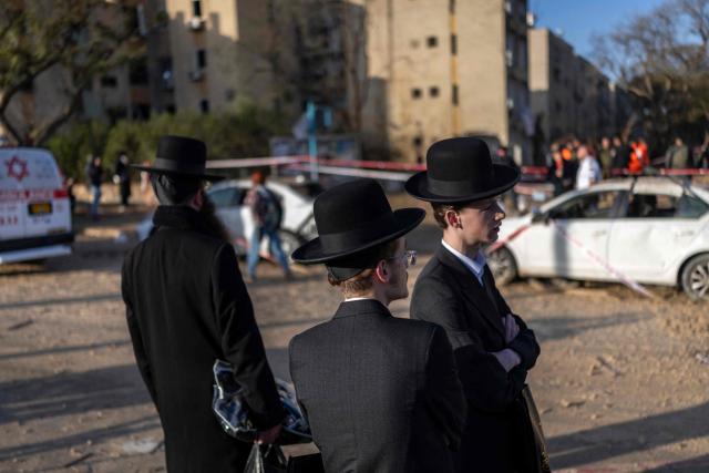 Israeli Orthodox Jews inspect the site of an Iranian missile strike in Arad on March 22, 2026. Iranian missile strikes on two southern Israeli towns wounded more than 100 people on March 21, medics said, after Israeli air defence systems failed to intercept the projectiles. (Photo by Ilia YEFIMOVICH / AFP) / 