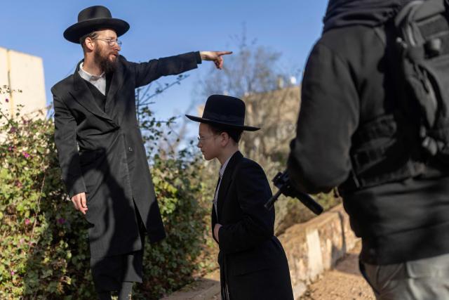 TOPSHOT - Israeli Orthodox Jews inspect the site of an Iranian missile strike in Arad on March 22, 2026. Iranian missile strikes on two southern Israeli towns wounded more than 100 people on March 21, medics said, after Israeli air defence systems failed to intercept the projectiles. (Photo by Ilia YEFIMOVICH / AFP) / 
