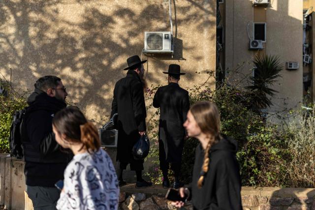 Israeli Orthodox Jews inspect the site of an Iranian missile strike in Arad on March 22, 2026. Iranian missile strikes on two southern Israeli towns wounded more than 100 people on March 21, medics said, after Israeli air defence systems failed to intercept the projectiles. (Photo by Ilia YEFIMOVICH / AFP) / 
