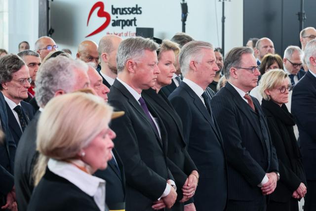 (From 4th L) Brussels Airport CEO Arnaud Feist, Queen Mathilde of Belgium, King Philippe - Filip of Belgium, Belgium's Prime Minister Bart De Wever and his partner Veerle Hegge stand at attention during the commemoration marking the 10th anniversary of the 2016 Brussels Airport terror attacks at the Brussels Airport in Zaventem on March 22, 2026. On March 22, 2016, 32 people were killed and 324 got injured in suicide bombings at Zaventem national airport and Maalbeek/ Maelbeek metro station, which were claimed by ISIL. (Photo by BENOIT DOPPAGNE / Belga / AFP) / Belgium OUT