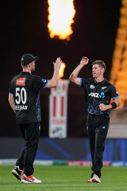 New Zealand captain Jimmy Neesham (L) celebrates catching South Africa's Tony de Zorzi with teammate Cole McConchie (R) during the fourth Twenty20 international cricket match between New Zealand and South Africa in Wellington on March 22, 2026. (Photo by Marty MELVILLE / AFP)
