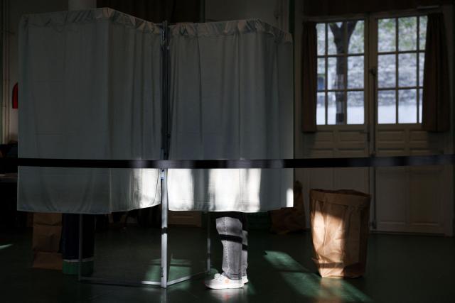 A local resident stands in a polling station to cast their vote during the second round of France's 2026 municipal elections in Paris on March 22, 2026. (Photo by Ian LANGSDON / AFP)