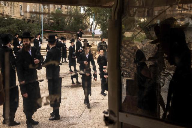 TOPSHOT - Israeli Orthodox Jews inspect the site of an Iranian missile strike in Arad on March 22, 2026. Iranian missile strikes on two southern Israeli towns wounded more than 100 people on March 21, medics said, after Israeli air defence systems failed to intercept the projectiles. (Photo by JOHN WESSELS / AFP) / 