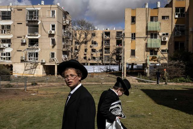 Israeli Orthodox Jews inspect the site of an Iranian missile strike in Arad on March 22, 2026. Iranian missile strikes on two southern Israeli towns wounded more than 100 people on March 21, medics said, after Israeli air defence systems failed to intercept the projectiles. (Photo by JOHN WESSELS / AFP) / 