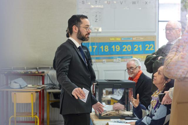 Roubaix' Left-wing La France Insoumise (LFI, Unbowed France) mayoral candidate David Guiraud (L) prepares to cast his vote during the second round of France's 2026 municipal elections in Roubaix, northern France on March 22, 2026. (Photo by Francois LO PRESTI / AFP)