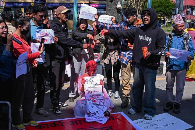 Activists spatter a woman with red powder to symbolize blood during a protest demanding the release of the inquiry report by a Nepal government investigation commission probing the September 2025 youth-led uprising that toppled the government, in Kathmandu on March 22, 2026. (Photo by Prakash MATHEMA / AFP)
