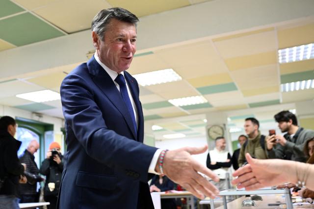 Nice's incumbent mayor and Horizons and Les Republicains (LR) candidate for re-election Christian Estrosi shakes hands with an electoral employee after casting his ballot during the second round of France's 2026 municipal elections in Nice, southeastern France on March 22, 2026. (Photo by Frederic DIDES / AFP)