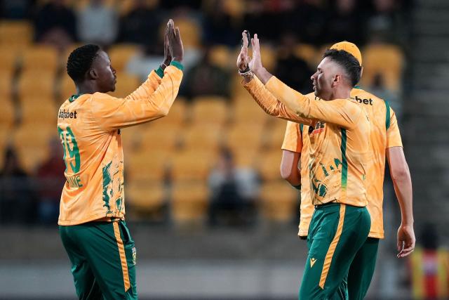 South Africa captain Keshav Maharaj (R) celebrates bowling New Zealand's Cole McConchie with teammate Andile Simelane during the fourth Twenty20 international cricket match between New Zealand and South Africa in Wellington on March 22, 2026. (Photo by Marty MELVILLE / AFP)