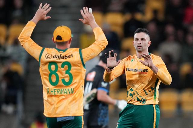 South Africa captain Keshav Maharaj (R) celebrates bowling New Zealand's Cole McConchie with teammate Rubin Hermann during the fourth Twenty20 international cricket match between New Zealand and South Africa in Wellington on March 22, 2026. (Photo by Marty MELVILLE / AFP)