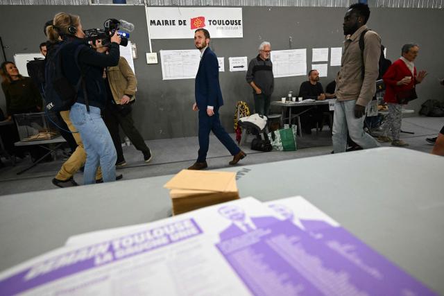 France's left-wing party La France Insoumise (LFI) MP and Toulouse's mayoral candidate François Piquemal (C) arrives to cast his vote during the second round of France's 2026 municipal elections in Toulouse, southwestern France on March 22, 2026. (Photo by Lionel BONAVENTURE / AFP)