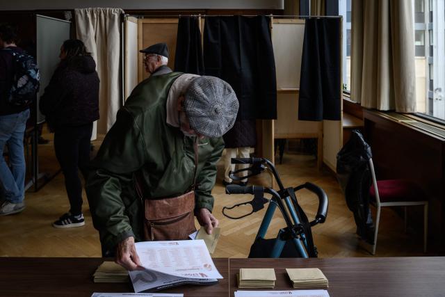 A local resident picks up a ballot before casting their vote during the second round of France's 2026 municipal elections in Lyon, central eastern France on March 22, 2026. (Photo by JEFF PACHOUD / AFP)