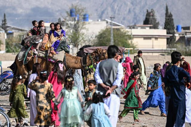Children ride a camel during Eid al-Fitr celebrations on the outskirts of Quetta on March 22, 2026. (Photo by Banaras KHAN / AFP)