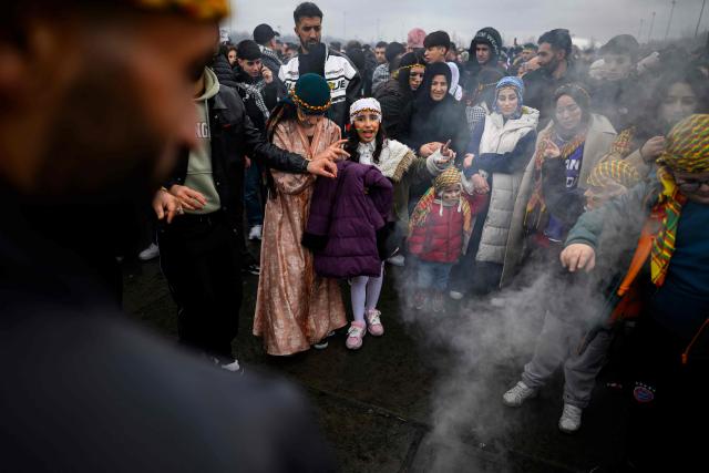 Members of the Kurdish community gather around a bonfire during a Kurdish celebration of the Nowruz (Noruz) marking the New Year of the Persian calendar and the first day of spring, in Istanbul on March 22, 2026. The Nowruz New Year is an ancient Zoroastrian tradition celebrated by Kurds and Iranians which coincides with the vernal (spring) equinox and is calculated by the solar calendar. (Photo by Yasin AKGUL / AFP)