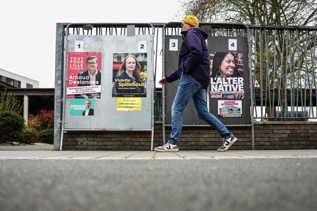 A pedestrian walks past campaign posters for the Lille mayoral candidates during the second round of France's 2026 municipal elections in Lille, northern France on March 22, 2026. (Photo by Sameer Al-DOUMY / AFP)