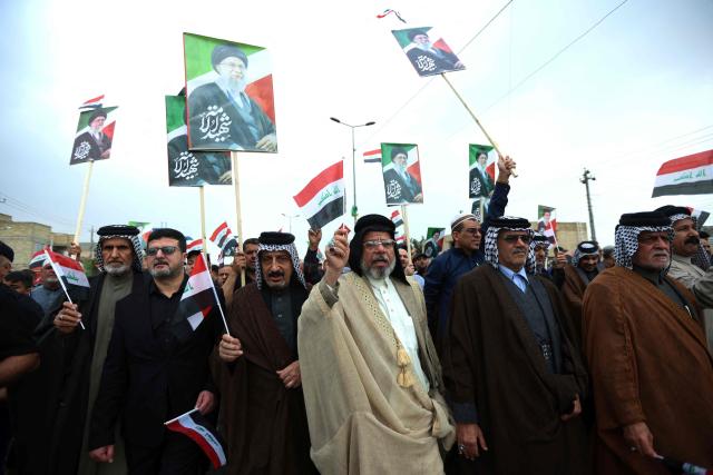 Waving the Iraqi flag and holding up placards with the image of the assassinated Iranian supreme leader Ayatollah Ali Khamenei, Iraqis rally in support of neighbouring Iran, in the al-Aamil district of Baghdad on March 22, 2026. On February 28, Israel and the United States launched strikes on Iran killing its supreme leader and triggering a war that spread across the Middle East and unleashed chaos across global markets and sent oil prices soaring. (Photo by MURTAJA LATEEF / AFP) / 