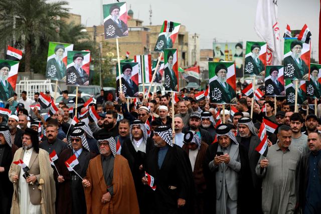 Waving the Iraqi flag and holding up placards with the image of the assassinated Iranian supreme leader Ayatollah Ali Khamenei, Iraqis rally in support of neighbouring Iran, in the al-Aamil district of Baghdad on March 22, 2026. On February 28, Israel and the United States launched strikes on Iran killing its supreme leader and triggering a war that spread across the Middle East and unleashed chaos across global markets and sent oil prices soaring. (Photo by Murtaja LATEEF / AFP) / 