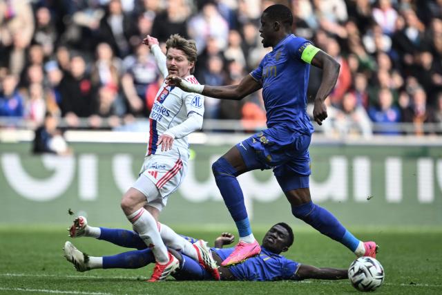 Lyon’s Czech midfielder #10 Pavel Sulc (L) is tackled by Monaco’s Senegalese midfielder #15 Lamine Camara (bottom) during the French L1 football match between Olympique Lyonnais (OL) and AS Monaco (ASM) at the Groupama Stadium in Decines-Charpieu, central-eastern France on March 22, 2026. (Photo by JEFF PACHOUD / AFP)