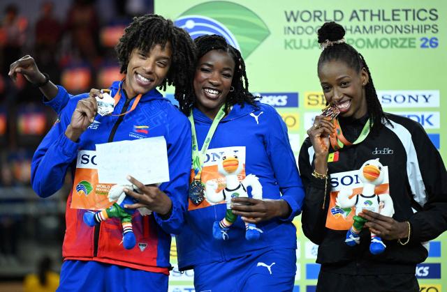 CORRECTION / Silver medallist Cuba's Leyanis Perez Hernandez (L), gold medallist Venezuela's Yulimar Rojas (C) and bronze medallist Senegal's Saly Sarr celebrate on the podium for the women's triple jump event during the World Athletics Indoor Championships Kujawy Pomorze 2026 in Torun, Poland on March 22, 2026. (Photo by Kirill KUDRYAVTSEV / AFP) / The erroneous mention[s] appearing in the metadata of this photo by Kirill KUDRYAVTSEV has been modified in AFP systems in the following manner: [Silver medallist Cuba's Leyanis Perez Hernandez (L), gold medallist Venezuela's Yulimar Rojas (C)] instead of [Silver medallist Cuba's Leyanis Perez Hernandez (C), gold medallist Venezuela's Yulimar Rojas (L)]. Please immediately remove the erroneous mention[s] from all your online services and delete it (them) from your servers. If you have been authorized by AFP to distribute it (them) to third parties, please ensure that the same actions are carried out by them. Failure to promptly comply with these instructions will entail liability on your part for any continued or post notification usage. Therefore we thank you very much for all your attention and prompt action. We are sorry for the inconvenience this notification may cause and remain at your disposal for any further information you may require.