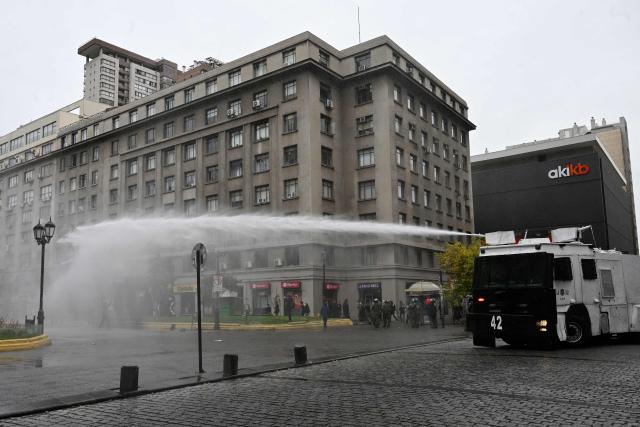 Protesters are sprayed by a police water cannon truck and a gas truck during a demonstration on World Water Day amid President Jose Antonio Kast's plans to roll back environmental protections in Santiago on March 22, 2026. (Photo by RODRIGO ARANGUA / AFP)