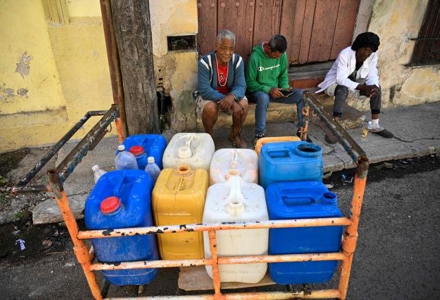 People queue to fill their water containers in Havana during a nationwide blackout on March 22, 2026. Cuban authorities scrambled on March 22 to restore power to the island after the second nationwide blackout in less than a week, as the grid struggles due to an aging infrastructure and a US oil blockade. (Photo by YAMIL LAGE / AFP)
