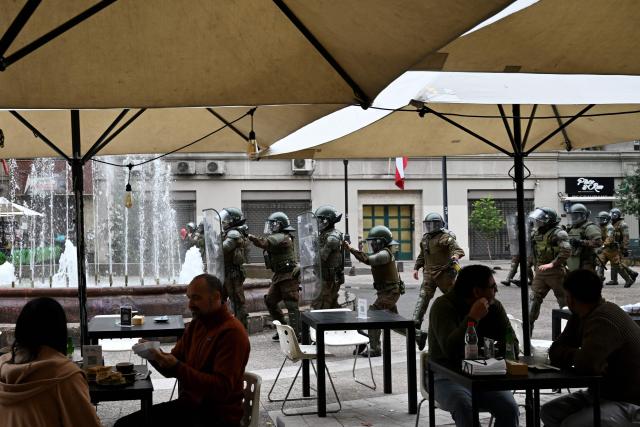 Riot police march past a cafe during a demonstration on World Water Day amid President Jose Antonio Kast's plans to roll back environmental protections in Santiago on March 22, 2026. (Photo by RODRIGO ARANGUA / AFP)