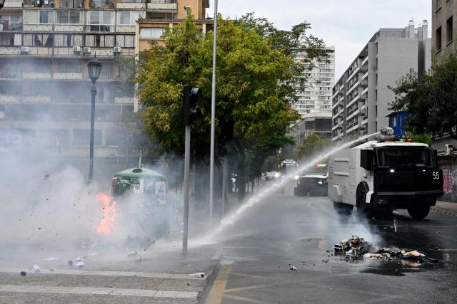 A police water cannon truck put out a fire during a demonstration on World Water Day amid President Jose Antonio Kast's plans to roll back environmental protections in Santiago on March 22, 2026. (Photo by RODRIGO ARANGUA / AFP)