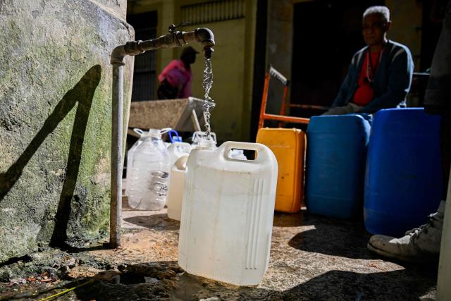 People queue to fill their water containers in Havana during a national blackout on March 22, 2026. Cuban authorities scrambled on March 22 to restore power to the island after the second nationwide blackout in less than a week, as the grid struggles due to an aging infrastructure and a US oil blockade. (Photo by YAMIL LAGE / AFP)