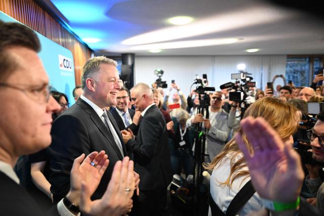 The conservative CDU party's top candidate for state elections in Rhineland-Palatinate Gordon Schnieder (2nd L) is applauded by supporters on March 22, 2026 at the regional parliament in Mainz, southwestern Germany, as first exit polls of Rhineland-Palatinate's state elections are being released. German Chancellor Friedrich Merz's conservative CDU party ousted the centre-left Social Democratic Party on Sunday in a closely watched state election in which the far right also made big gains, according to exit polls. The CDU took around 30 percent of the vote to win the western state of Rhineland-Palatinate away from the SPD after 35 years, while the far-right Alternative for Germany party (AfD) looked set for a record score in western Germany, with around 20 percent, according to two public TV networks' exit polls. (Photo by DANIEL PETER / AFP)