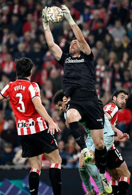 Athletic Bilbao's Spanish goalkeeper #01 Unai Simon jumps to make a save despite being challenged by Real Betis' Moroccan forward #10 Abde Ezzalzouli (2L) during the Spanish league football match between Athletic Club Bilbao and Real Betis at San Mames Stadium in Bilbao on March 22, 2026. (Photo by ANDER GILLENEA / AFP)