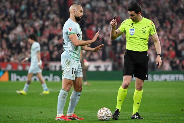 Real Betis' Moroccan midfielder #14 Sofyan Amrabat speaks with Spanish referee Alejandro Muniz during the Spanish league football match between Athletic Club Bilbao and Real Betis at San Mames Stadium in Bilbao on March 22, 2026. (Photo by ANDER GILLENEA / AFP)