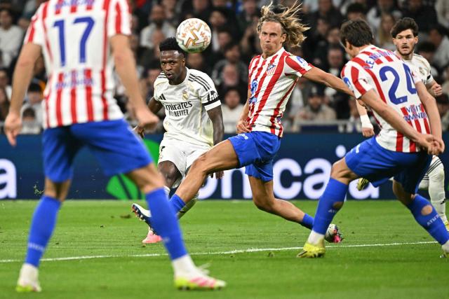 Real Madrid's Brazilian forward #07 Vinicius Junior (CL) shoots past Atletico Madrid's Spanish midfielder #14 Marcos Llorente (CR) during the Spanish league football match between Real Madrid CF and Club Atletico de Madrid at Santiago Bernabeu Stadium in Madrid on March 22, 2026. (Photo by Javier SORIANO / AFP)