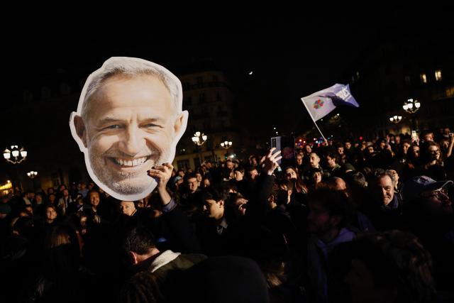 Supporters waves a placard depicting Socialistes et Apparentes' MP and Paris' Mayoral candidate Emmanuel Gregoire after his victory following the announcement of official results of the second round of France's 2026 municipal elections at Paris townhall in Paris on March 22, 2026. (Photo by Kenzo TRIBOUILLARD / AFP)
