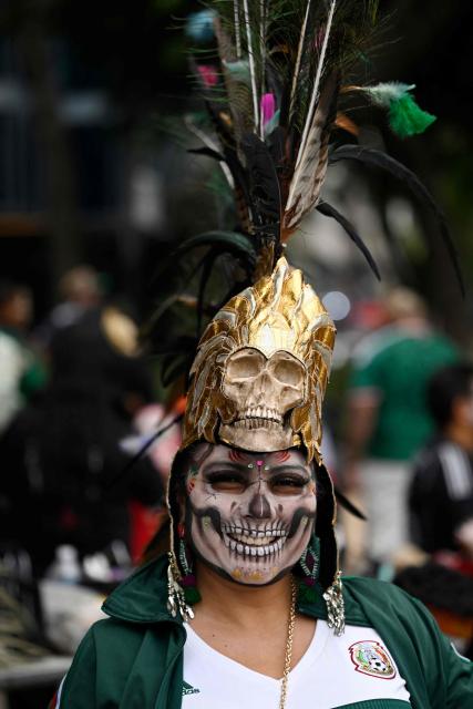 A woman with her face painted looks on as she takes part in a procession of Catrinas wearing the Mexican World Cup national football team jersey in Mexico City on March 22, 2026. (Photo by Alfredo ESTRELLA / AFP)