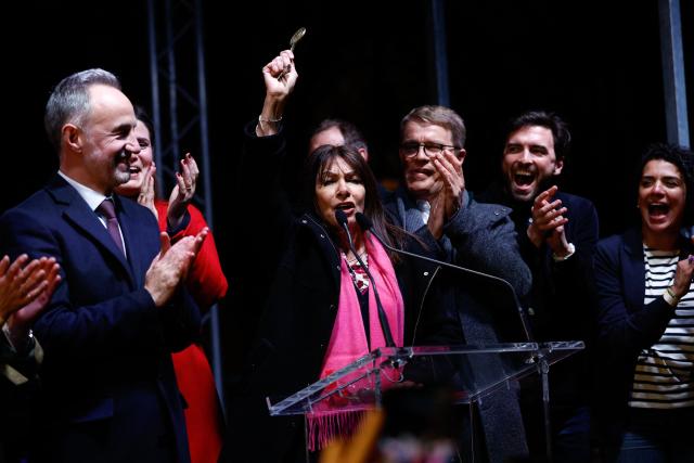 Former Paris' mayor Anne Hidalgo (C) holds the key of Paris before delivering it to Socialistes et Apparentes' MP and Paris' Mayoral candidate Emmanuel Gregoire as he celebrates his victory following the announcement of official results of the second round of France's 2026 municipal elections at Paris townhall in Paris on March 22, 2026. (Photo by Kenzo TRIBOUILLARD / AFP)