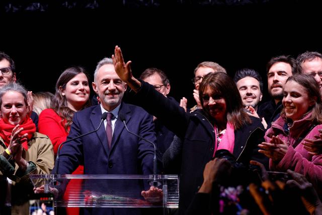 Paris outgoing Mayor Anne Hidalgo (C-R) waves flanked by Socialist Party (PS) Member of Parliament and left wing Paris mayoral candidate Emmanuel Gregoire (C-L) during a gathering following the second round of France's 2026 municipal elections in Paris on March 22, 2026. Gregoire was elected Paris mayor in the French capital's municipal elections. (Photo by GEOFFROY VAN DER HASSELT / AFP)