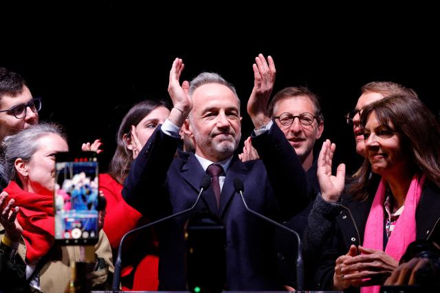 Socialist Party (PS) Member of Parliament and left wing Paris mayoral candidate Emmanuel Gregoire (C) reacts next to  Paris outgoing Mayor Anne Hidalgo (R) during a gathering following the second round of France's 2026 municipal elections in Paris on March 22, 2026. Gregoire was elected Paris mayor in the French capital's municipal elections. (Photo by GEOFFROY VAN DER HASSELT / AFP)
