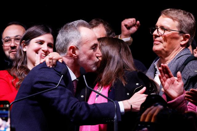 Socialist Party (PS) Member of Parliament and left wing Paris mayoral candidate Emmanuel Gregoire (L) embraces  Paris outgoing Mayor Anne Hidalgo (R) during a gathering following the second round of France's 2026 municipal elections in Paris on March 22, 2026. Gregoire was elected Paris mayor in the French capital's municipal elections. (Photo by GEOFFROY VAN DER HASSELT / AFP)