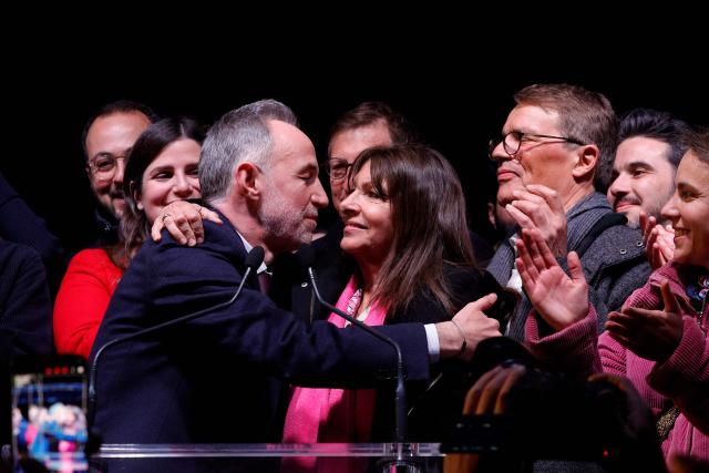 Socialist Party (PS) Member of Parliament and left wing Paris mayoral candidate Emmanuel Gregoire (L) embraces  Paris outgoing Mayor Anne Hidalgo (R) during a gathering following the second round of France's 2026 municipal elections in Paris on March 22, 2026. Gregoire was elected Paris mayor in the French capital's municipal elections. (Photo by GEOFFROY VAN DER HASSELT / AFP)