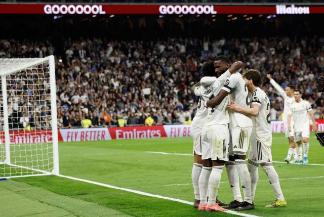 Real Madrid's players celebrate their third goal scored by Brazilian forward #07 Vinicius Junior celebrates scoring his team's third goal during the Spanish league football match between Real Madrid CF and Club Atletico de Madrid at Santiago Bernabeu Stadium in Madrid on March 22, 2026. (Photo by Oscar DEL POZO / AFP)