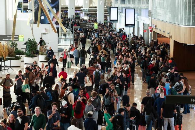 Passengers queue to go through security at New York's LaGuardia airport on Marh 22, 2026. Immigration agents will be deployed in US airports beginning March 23, aiming to alleviate soaring congestion at security screenings amid a weeks-long budget standoff over President Donald Trump's mass deportation drive, officials said. Trump announced the extraordinary move in a social media post Sunday morning, sending officials racing to quickly develop a plan. (Photo by CHARLY TRIBALLEAU / AFP)