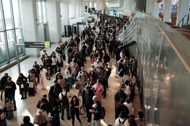 Passengers queue to go through security at New York's LaGuardia airport on Marh 22, 2026. Immigration agents will be deployed in US airports beginning March 23, aiming to alleviate soaring congestion at security screenings amid a weeks-long budget standoff over President Donald Trump's mass deportation drive, officials said. Trump announced the extraordinary move in a social media post Sunday morning, sending officials racing to quickly develop a plan. (Photo by CHARLY TRIBALLEAU / AFP)