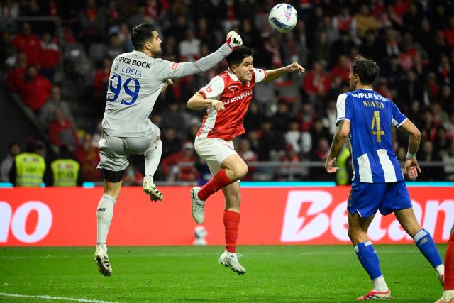 FC Porto's Portuguese goalkeeper #99 Diogo Costa punches the ball past Sporting Braga's Spanish forward #39 Fran Navarro during the Portuguese League football match between SC Braga and FC Porto at Municipal stadium of Braga on March 22, 2026. (Photo by Miguel RIOPA / AFP)