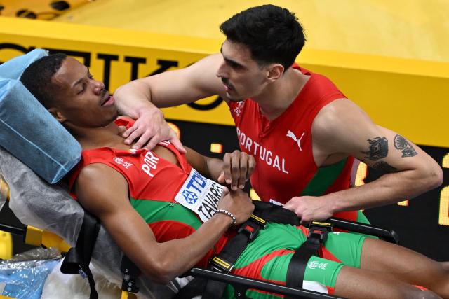 Portugal's Ericsson Tavares (L) reacts with a team member as he is taken away on a stretcher after an injury in the men's final 4x400 metres relay event during the World Athletics Indoor Championships Kujawy Pomorze 2026 in Torun, Poland on March 22, 2026. (Photo by Andrej ISAKOVIC / AFP)