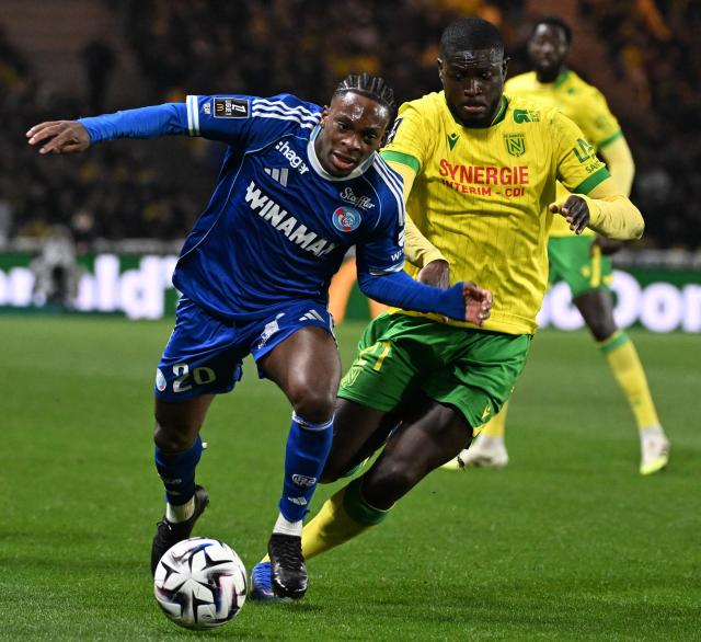 Strasbourg's Ivorian forward #20 Martial Godo (C) vies with Nantes' French midfielder #21 Mohamed Kaba (R) during the French L1 football match between Nantes and Strasbourg at La Beaujoire stadium in Nantes, western France, on March 22, 2026. (Photo by Sebastien Salom-Gomis / AFP)