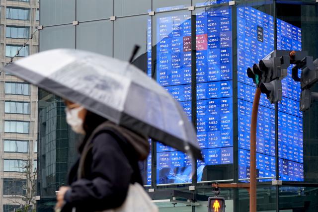 A pedestrian walks past an electronic quotation board displaying the Nikkei 225 stock prices on the Tokyo Stock Exchange in Tokyo on March 23, 2026. (Photo by Kazuhiro NOGI / AFP)