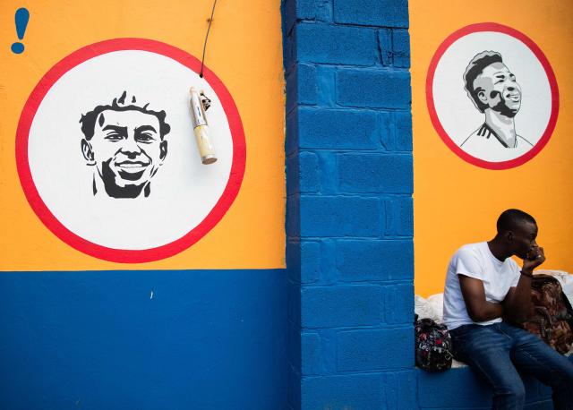 A man sits in front of a wall with portraits of footballers Lamine Yamal and Vinicius Junior in Delmas, Port-au-Prince, Haiti, on March 22, 2026. (Photo by Clarens SIFFROY / AFP)