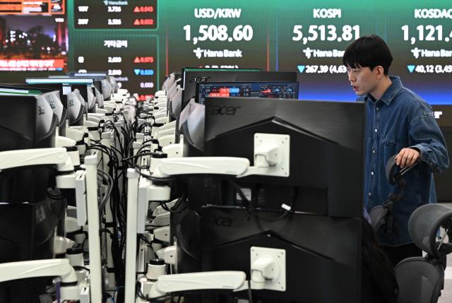 A currency dealer monitors exchange rates as a screen shows South Korea's benchmark stock index (KOSPI) and the Korean won/USD exchange rate (C) in a foreign exchange dealing room at the Hana Bank headquarters in Seoul on March 23, 2026. South Korea's won dropped to its weakest level against the US dollar in 17 years in early trading on March 23, amid market volatility sparked by the Iran war. (Photo by Jung Yeon-je / AFP)