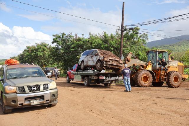 A destroyed car is moved off the road after the Kona Low storm flood devastated the Otake Camp community in Waialua, Hawaii, on March 22, 2026. Severe rains have battered the region over the weekend prompting officials to order evacuations. (Photo by Marco GARCIA / AFP)