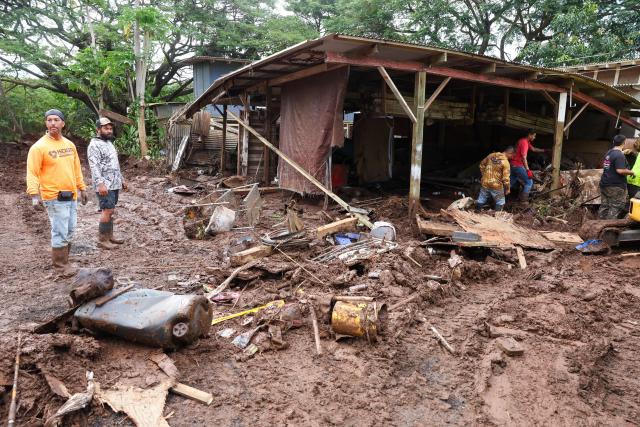 Residents and volunteers work on cleaning up after the Kona Low storm flood that devastated the Otake Camp community in Waialua, Hawaii, on March 22, 2026. Severe rains have battered the region over the weekend prompting officials to order evacuations. (Photo by Marco GARCIA / AFP)